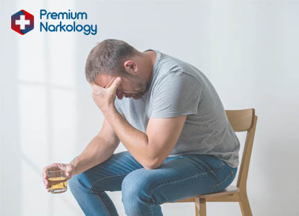 Мужчина с бутылкой в руке сидит на стуле