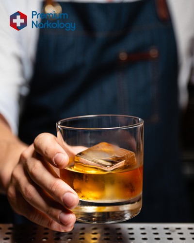 Мужчина протягивает стакан с алкоголем