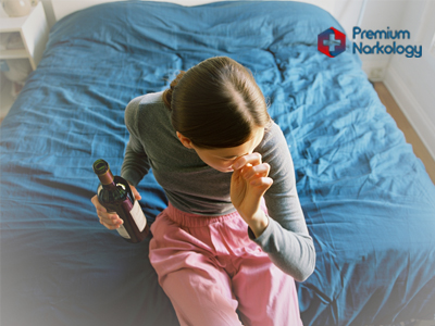 Женщина в пижаме пьёт вино на кровати