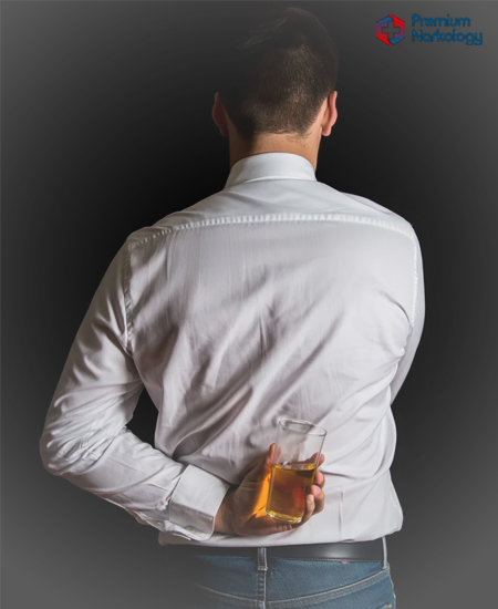 Мужчина стоит спиной и держит стакан с алкоголем