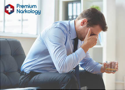 Мужчина со стаканом алкоголя держится за голову