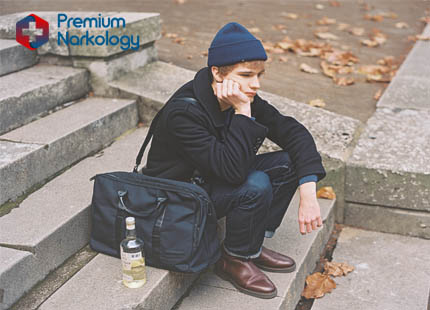 Парень сидит на лестнице с бутылкой вина