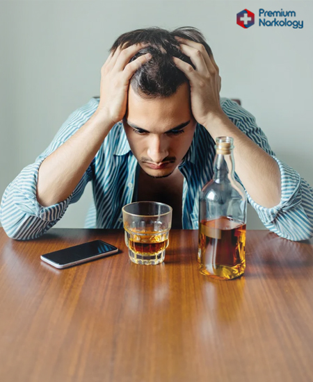 Мужчина сидит за столом с алкоголем