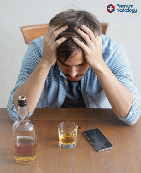 Мужчина сидит за столом с алкоголем